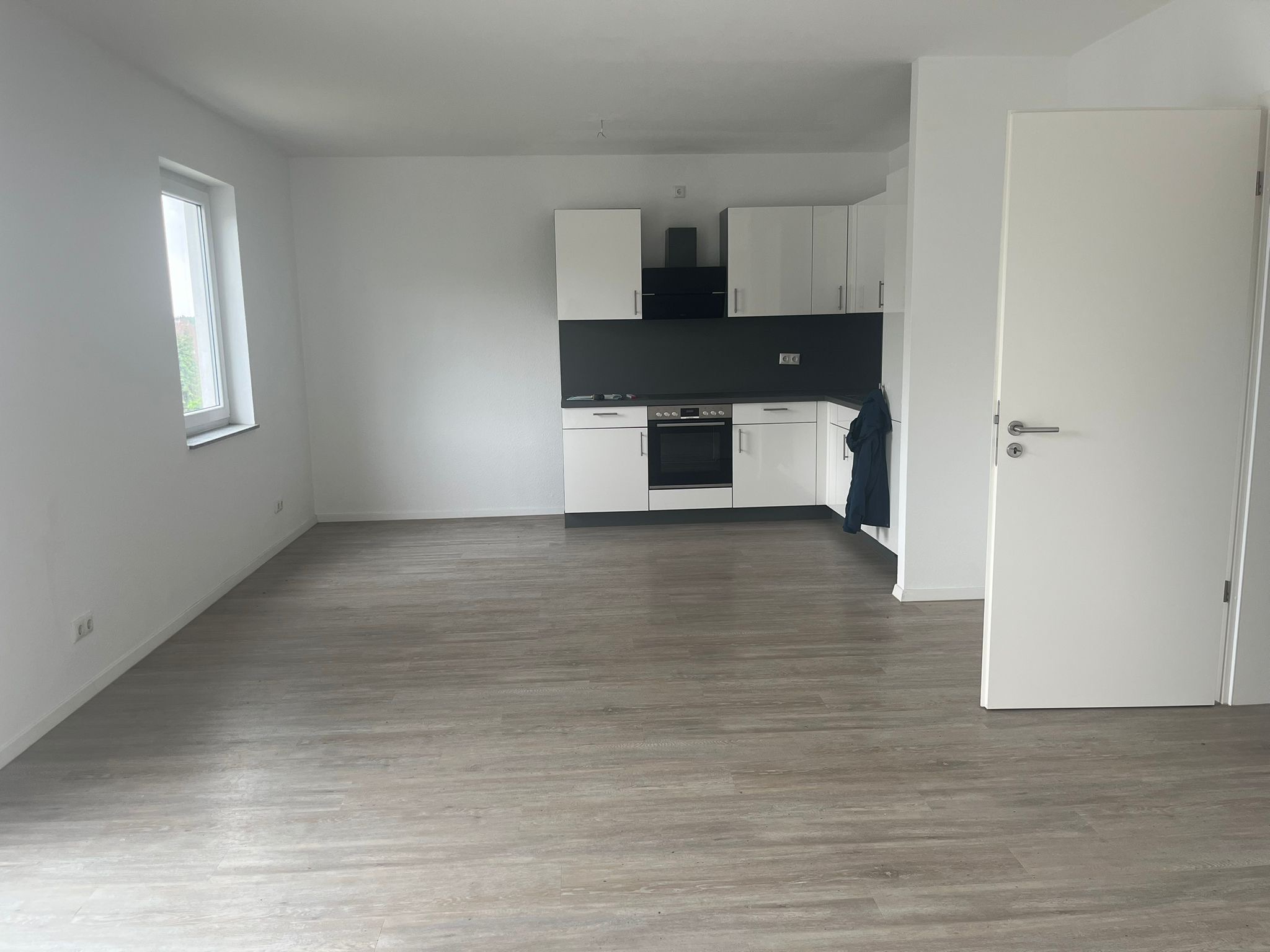 Renovierte Wohnung in Köln mit frisch gestrichenen weißen Wänden, Einbauküche und neuem Bodenbelag