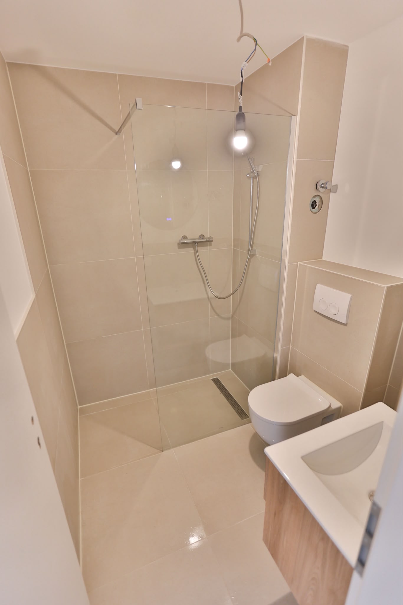 Modernes Badezimmer nach Badsanierung in Köln mit großformatigen Fliesen, bodengleicher Dusche, Glasduschwand und Q4 gespachtelten Wänden