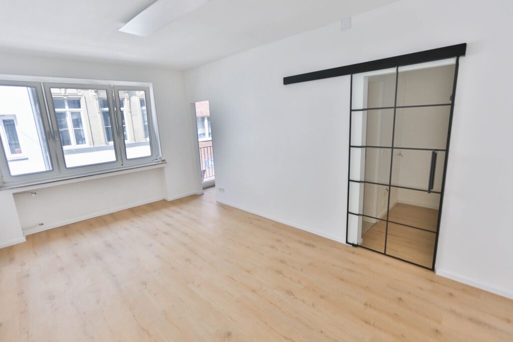 Wohnungsrenovierung in Köln mit Q4 Spachtelarbeiten, weißen Wänden, Vinylboden, Fußleisten und moderner Glasschiebetür